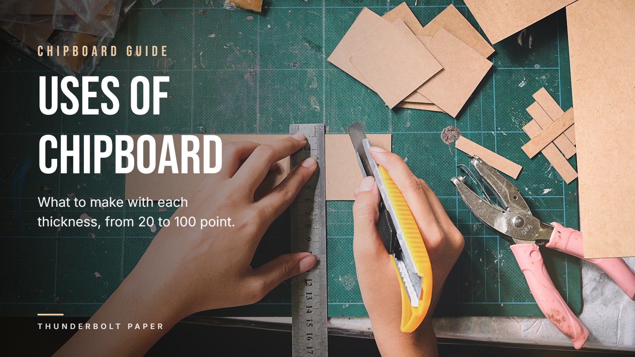 Hands cutting a strip of brown chipboard with a ruler and a craft knife on a cutting mat