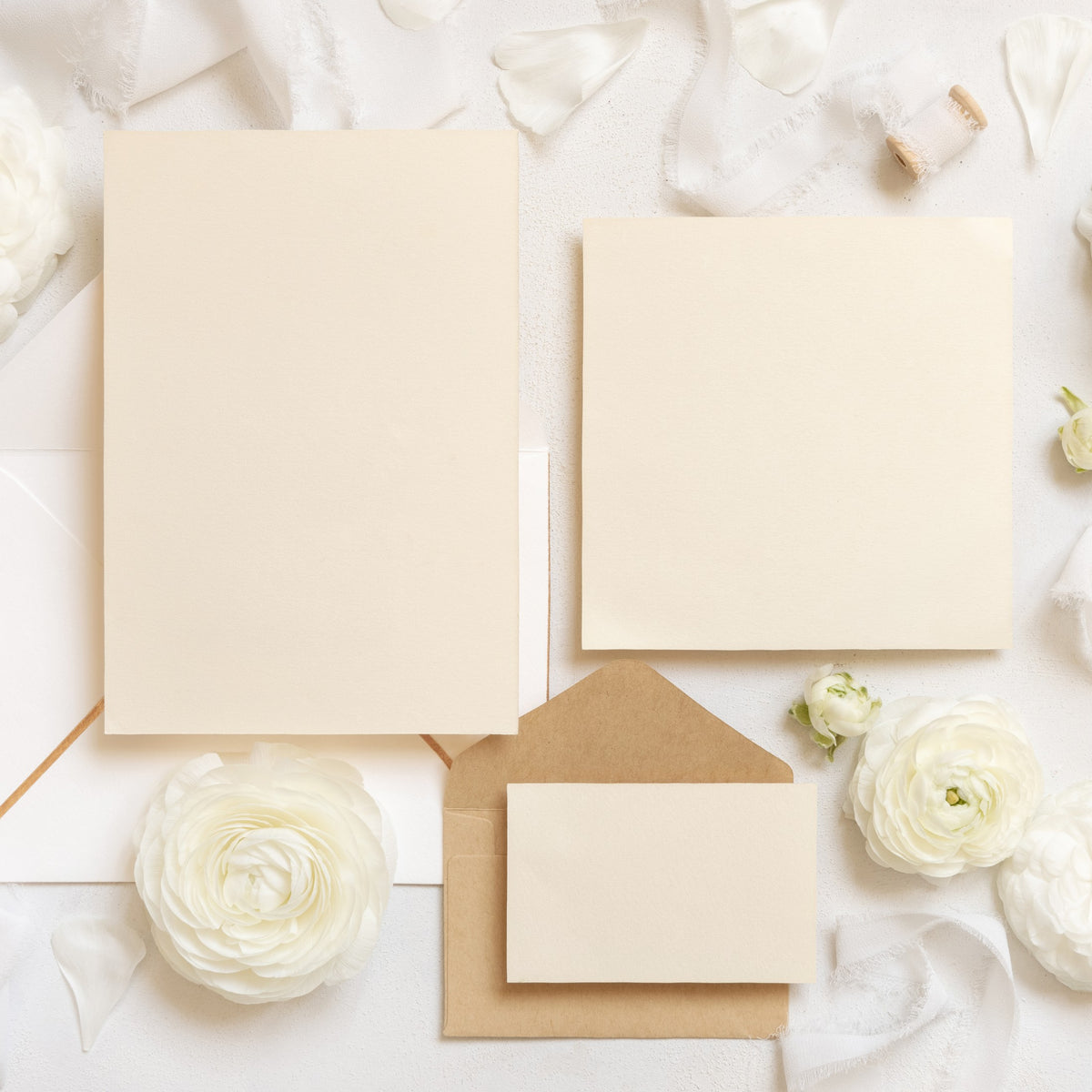 Cream invitation cards with a kraft envelope and white flowers